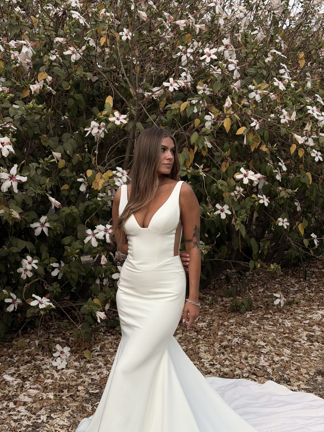 Bride in a fitted ivory gown among white blossoms